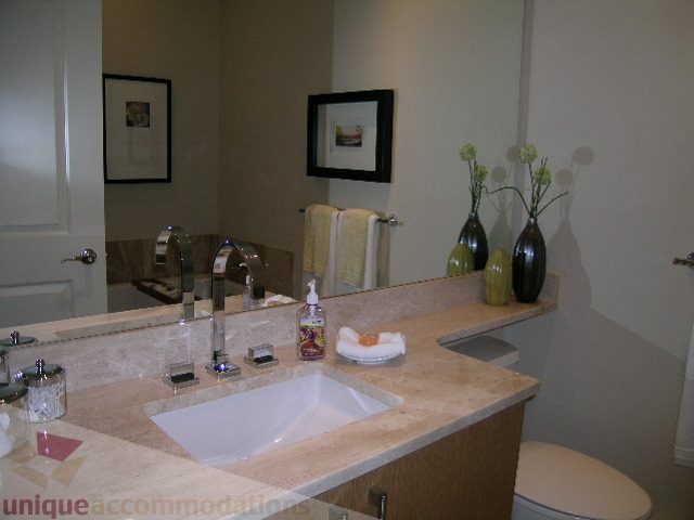 Bathroom with marble countertop and modern sink, vase with flowers on counter. - 102 - 1333 West 11th Ave., Vancouver West Side