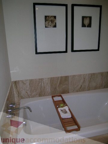 Furnished bathroom with white tub, wooden towel rack, and framed flower prints. - 102 - 1333 West 11th Ave., Vancouver West Side