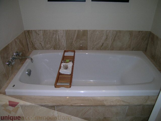 Furnished bathroom with marble tiles and a modern bathtub setup. - 102 - 1333 West 11th Ave., Vancouver West Side