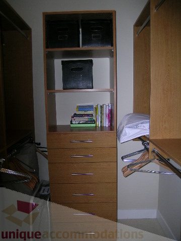 Furnished bedroom with wooden shelves, storage bins, and hangers. - 102 - 1333 West 11th Ave., Vancouver West Side