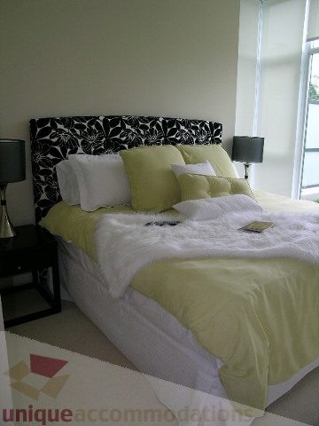 Spacious bedroom with a stylish black and white floral headboard and vibrant green bedding. - 102 - 1333 West 11th Ave., Vancouver West Side