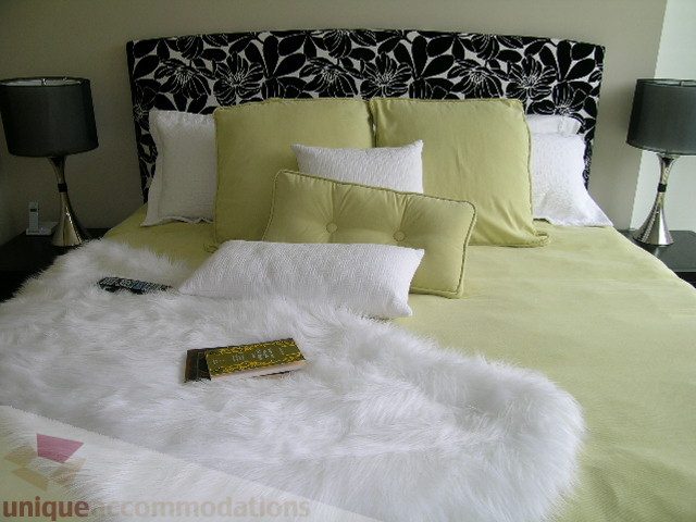 Furnished bedroom with a floral headboard, plush white fur throw, and lime green bedding. - 102 - 1333 West 11th Ave., Vancouver West Side