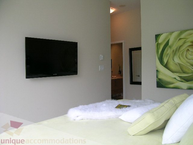Bright bedroom with modern decor, large TV, and floral artwork. - 102 - 1333 West 11th Ave., Vancouver West Side