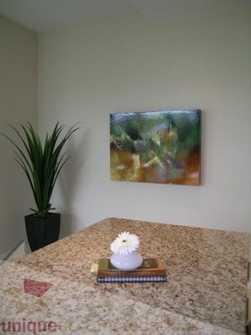 Bright kitchen with granite countertops, a vase of flowers, and a modern abstract painting on the wall.
