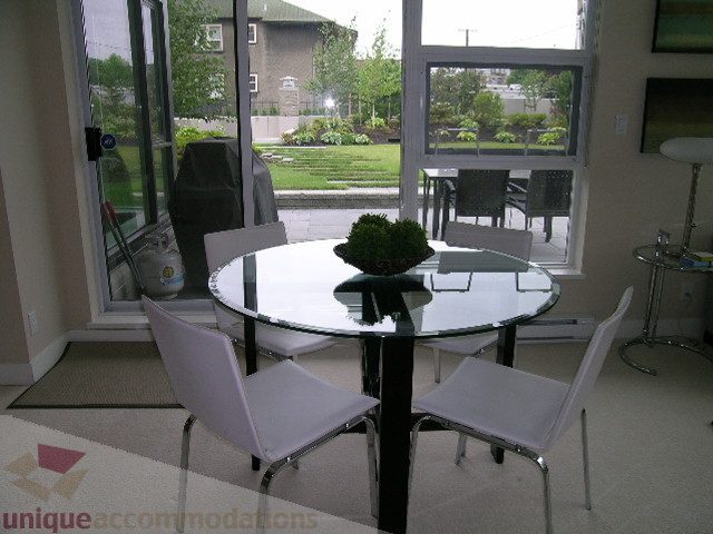 Furnished dining area with glass table and white chairs, city view through sliding glass doors. - 102 - 1333 West 11th Ave., Vancouver West Side