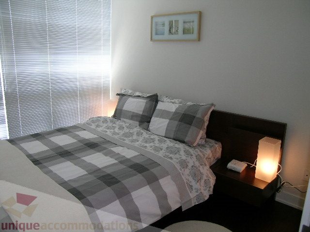 Spacious bedroom with checkered bedding and bedside lamps, perfect for a cozy stay. - 1209 - 1055 Richards Street, Vancouver Downtown