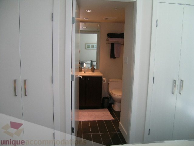 Spacious bedroom with white cabinets and a cozy bathroom access. - 1209 - 1055 Richards Street, Vancouver Downtown