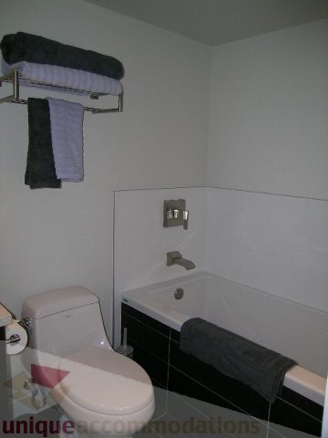 Modern bathroom with white walls, black tiled floor, and a sleek bathtub. - 1209 - 1055 Richards Street, Vancouver Downtown