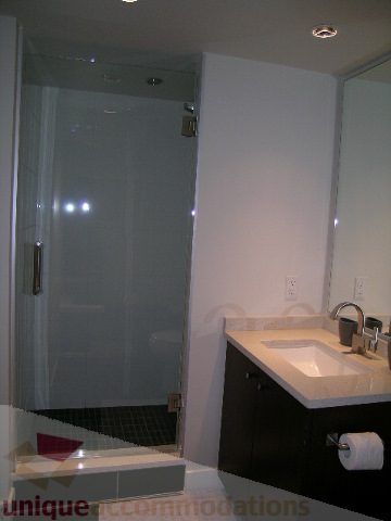 Modern bathroom with sleek white countertops and a glass-enclosed shower. - 1209 - 1055 Richards Street, Vancouver Downtown