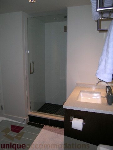 Spacious bathroom with modern sink, glass shower, and dark wood vanity. - 1209 - 1055 Richards Street, Vancouver Downtown