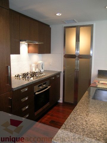 Modern kitchen with granite countertops, dark wood cabinets, and stainless steel appliances. - 1209 - 1055 Richards Street, Vancouver Downtown