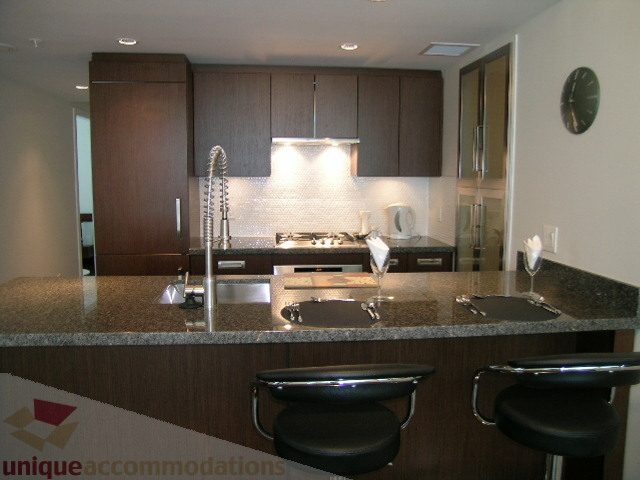 Modern kitchen with sleek granite countertops and dark wood cabinets. - 1209 - 1055 Richards Street, Vancouver Downtown