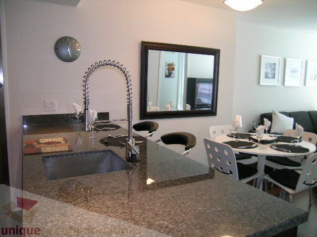 Modern kitchen with granite countertops and a large mirror reflecting the dining area. - 1209 - 1055 Richards Street, Vancouver Downtown