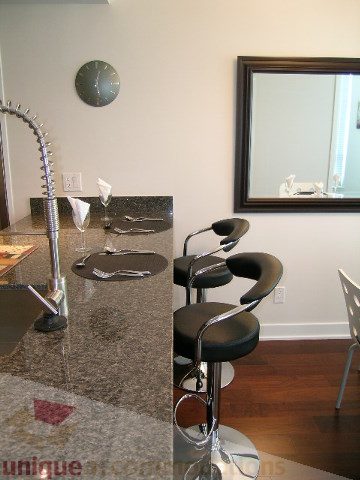 Modern kitchen with granite countertops, bar stools, and hardwood floors. - 1209 - 1055 Richards Street, Vancouver Downtown