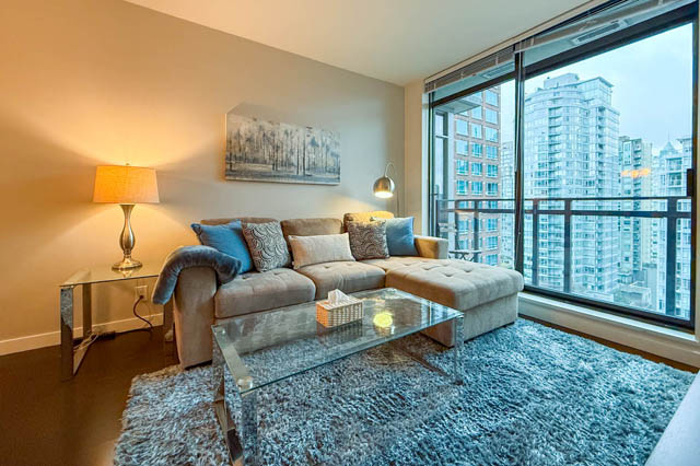 Modern living room with a city view, furnished sectional sofa, and glass coffee table. - 1802 - 788 Richards, Vancouver Downtown