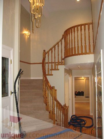 Staircase with wooden banister leading to upper level; modern chandelier above. - 2737 Mahon Ave., North Vancouver