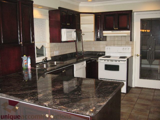 Bright kitchen with dark granite countertops and dark wood cabinets. - 2737 Mahon Ave., North Vancouver