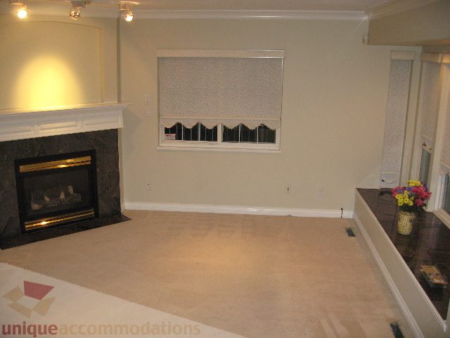 Bright living room with beige carpet, dark countertops, and a fireplace. - 2737 Mahon Ave., North Vancouver