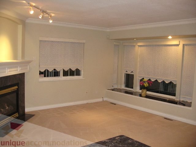 Spacious living room with large windows, fireplace, and patterned carpet. - 2737 Mahon Ave., North Vancouver