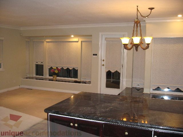 Bright kitchen with dark granite countertops and a chandelier, spacious and well-lit. - 2737 Mahon Ave., North Vancouver