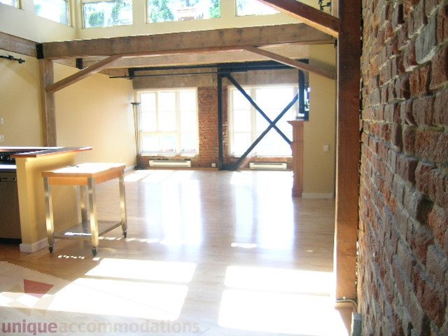 Bright kitchen with wooden beams, brick wall, and hardwood floors. - 408 - 1066 Hamilton Street, Vancouver Downtown