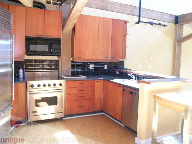 Bright kitchen with stainless steel appliances, hardwood floors, and wooden cabinetry. - 408 - 1066 Hamilton Street, Vancouver Downtown