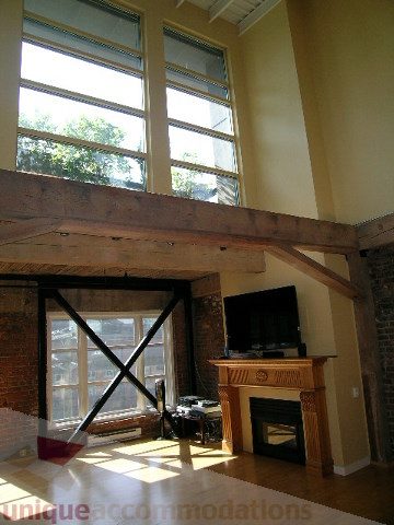 Bright living room with exposed beams, hardwood floors, and a fireplace. - 408 - 1066 Hamilton Street, Vancouver Downtown