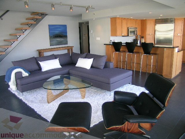 Furnished living room with modern furniture, hardwood floors, and a city view. - 310 - 990 Beach, Vancouver Downtown