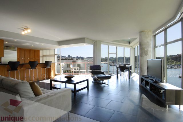 Furnished living room with large windows, city view, and modern furniture. - 310 - 990 Beach, Vancouver Downtown