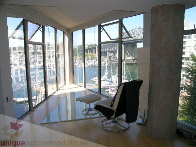 Bright living room with large windows, city view, and modern furniture. - 310 - 990 Beach, Vancouver Downtown