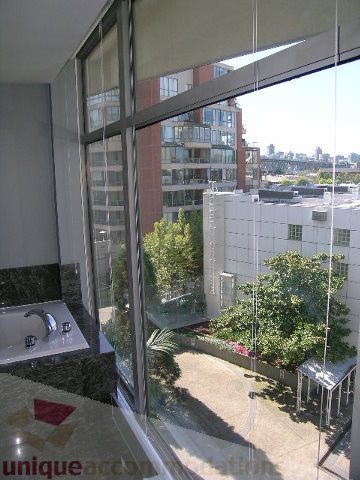 Bright living room with large windows, city view, and modern furnishings. - 310 - 990 Beach, Vancouver Downtown