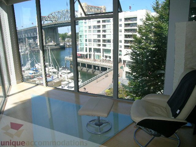 Bright living room with glass coffee table, city view, and waterfront access. - 310 - 990 Beach, Vancouver Downtown