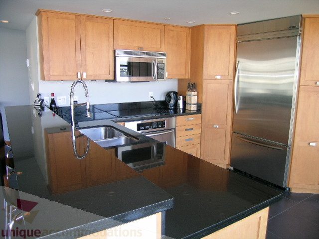 Bright kitchen with modern appliances, granite countertops, and wooden cabinets. - 310 - 990 Beach, Vancouver Downtown