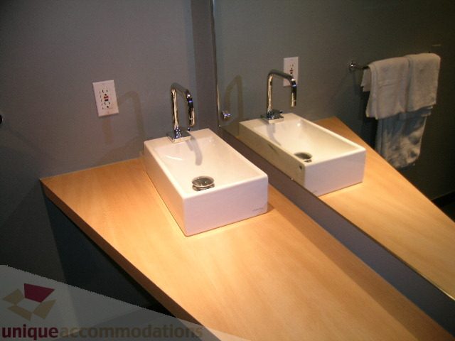 Bright bathroom with modern sink and mirror, light wood countertop. - 310 - 990 Beach, Vancouver Downtown