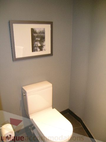 Bathroom with modern toilet and framed artwork on wall. - 310 - 990 Beach, Vancouver Downtown