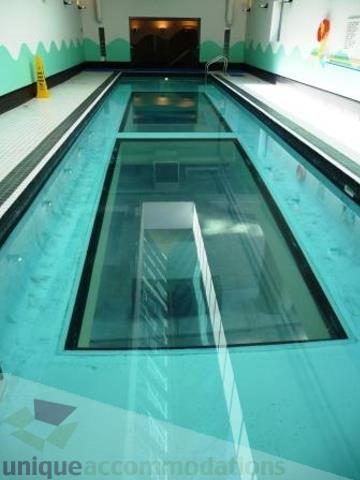 Futuristic glass-walled pool with vibrant blue water, modern design. - 310 - 990 Beach, Vancouver Downtown
