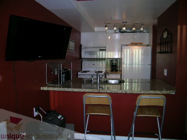 Bright kitchen with granite countertops, modern appliances, and a flat-screen TV mounted on the wall. - 1403 - 555 Jervis Street, Vancouver Downtown