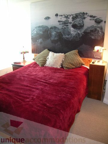 Furnished 1-bedroom with red bedding and a large rock mural. - 1403 - 555 Jervis Street, Vancouver Downtown