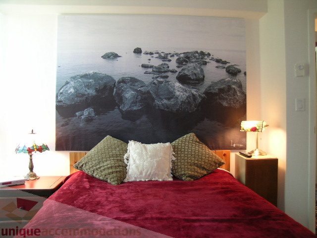 Furnished bedroom with a large ocean rock mural and red velvet bedding. - 1403 - 555 Jervis Street, Vancouver Downtown