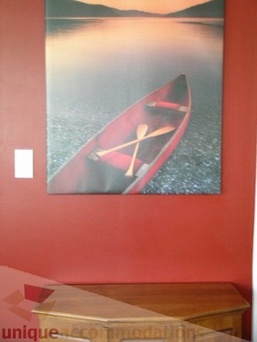 Bright living room with red wall art of a canoe and lake, wooden coffee table. - 1403 - 555 Jervis Street, Vancouver Downtown