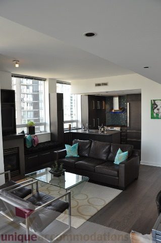 Bright living room with modern furniture, city view, and hardwood floors. - 2702 - 638 Beach Crescent, Vancouver Downtown