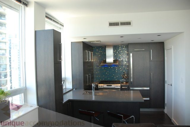 Bright kitchen with modern appliances, blue mosaic backsplash, and city view. - 2702 - 638 Beach Crescent, Vancouver Downtown