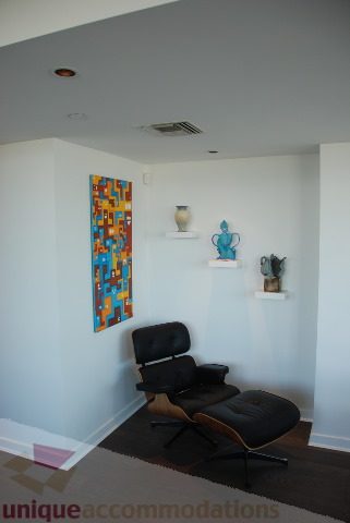 Furnished living room with modern chair, colorful abstract art, and white walls. - 2702 - 638 Beach Crescent, Vancouver Downtown