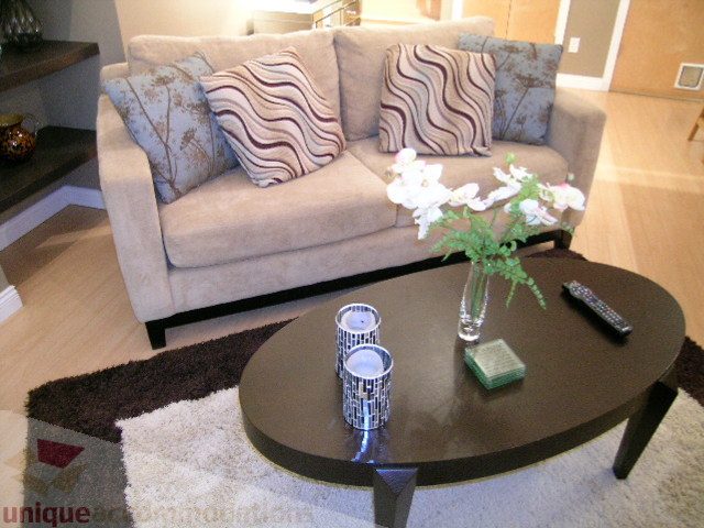 Living room with beige sofa, patterned cushions, and dark coffee table with vase and remote. - 981 Richards Street, Vancouver Downtown
