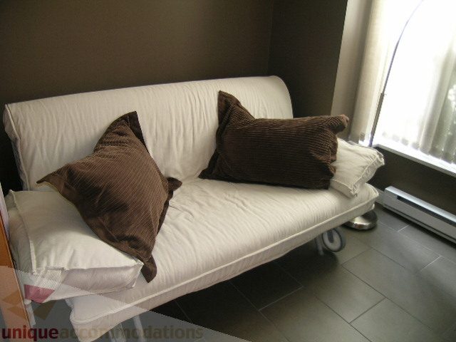 Bright living room with white sofa, brown cushions, and large window with sheer curtains. - 981 Richards Street, Vancouver Downtown