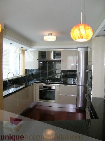 Bright kitchen with modern appliances, dark countertops, and pendant lights. - 603 - 1383 Marinaside Crescent, Vancouver Downtown