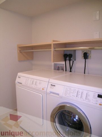 Laundry room with white appliances, wooden shelves, and power outlets. - 603 - 1383 Marinaside Crescent, Vancouver Downtown