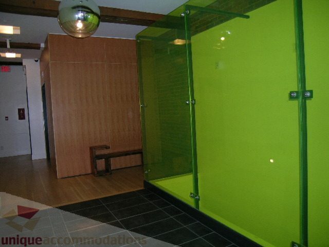 Bright living room with vibrant green walls and glass partitions, hardwood floors, and a modern disco ball.
