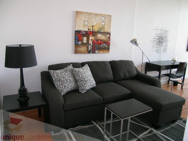 Furnished living room with modern sectional sofa, abstract art, and black table lamps. - 902 - 528 Beatty Street, Vancouver Downtown