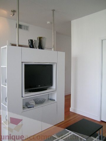 Bright living room with white cabinets, hardwood floors, and a modern TV setup. - 902 - 528 Beatty Street, Vancouver Downtown